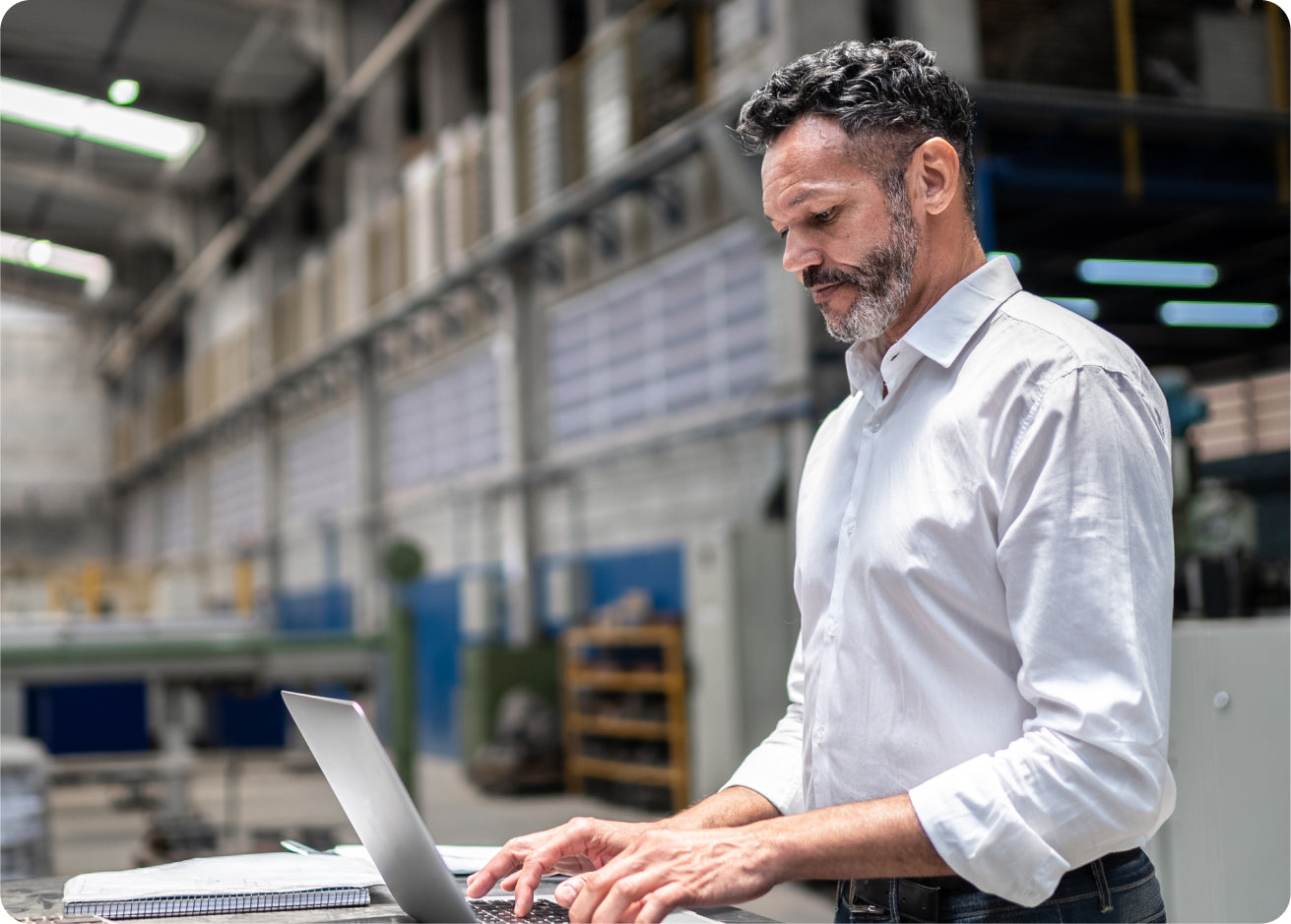 Man using a laptop in a warehouse setting