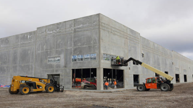 Under construction building with heavy machinery and workers on a cloudy day