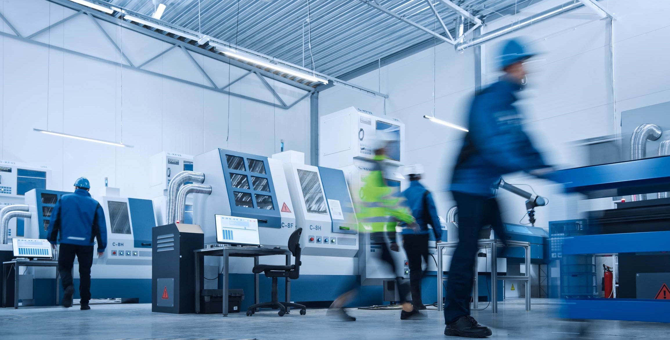 Factory floor with workers and machinery, emphasizing industrial setting.