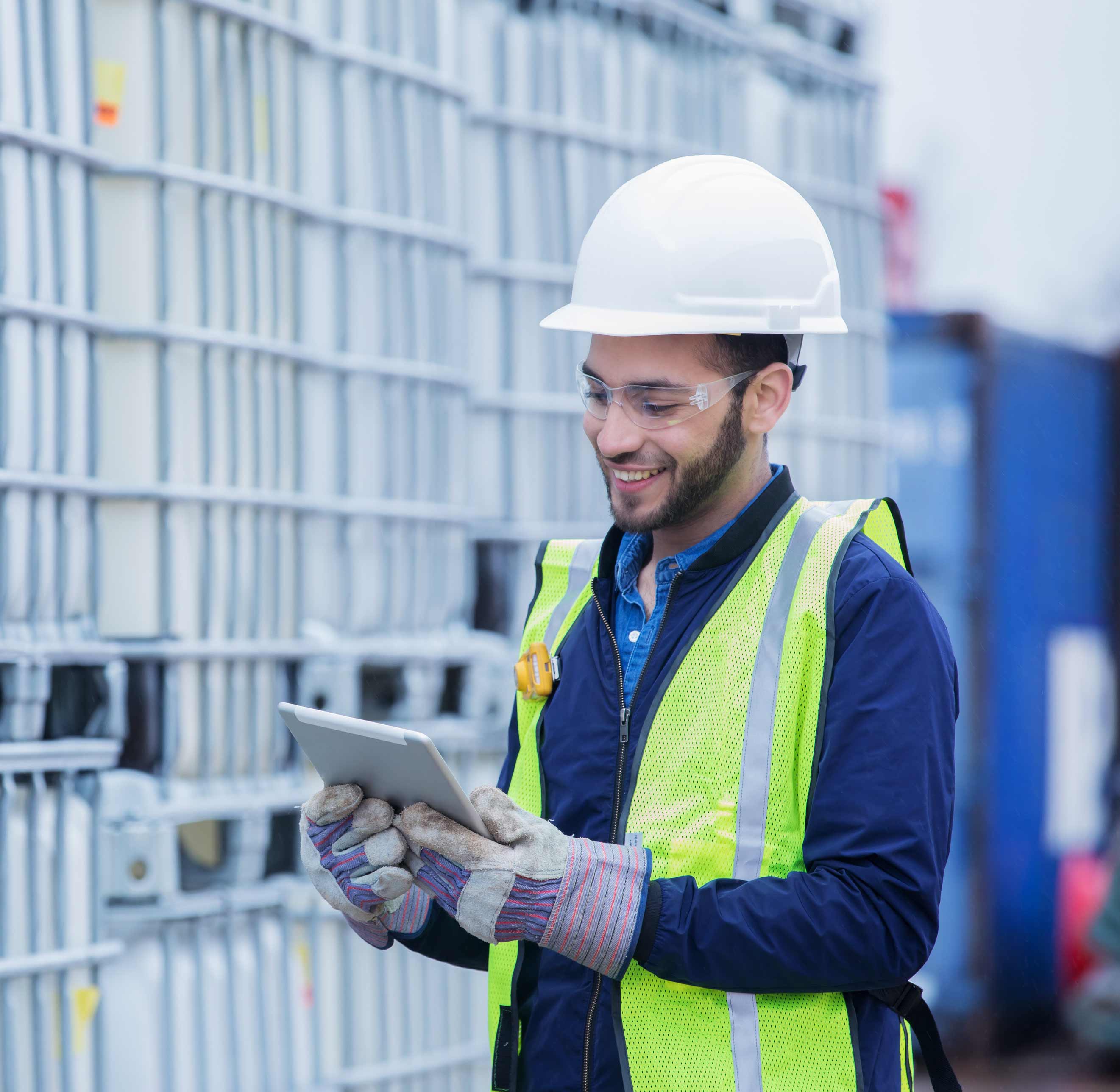 Man in safety gear using a tablet in an industrial setting