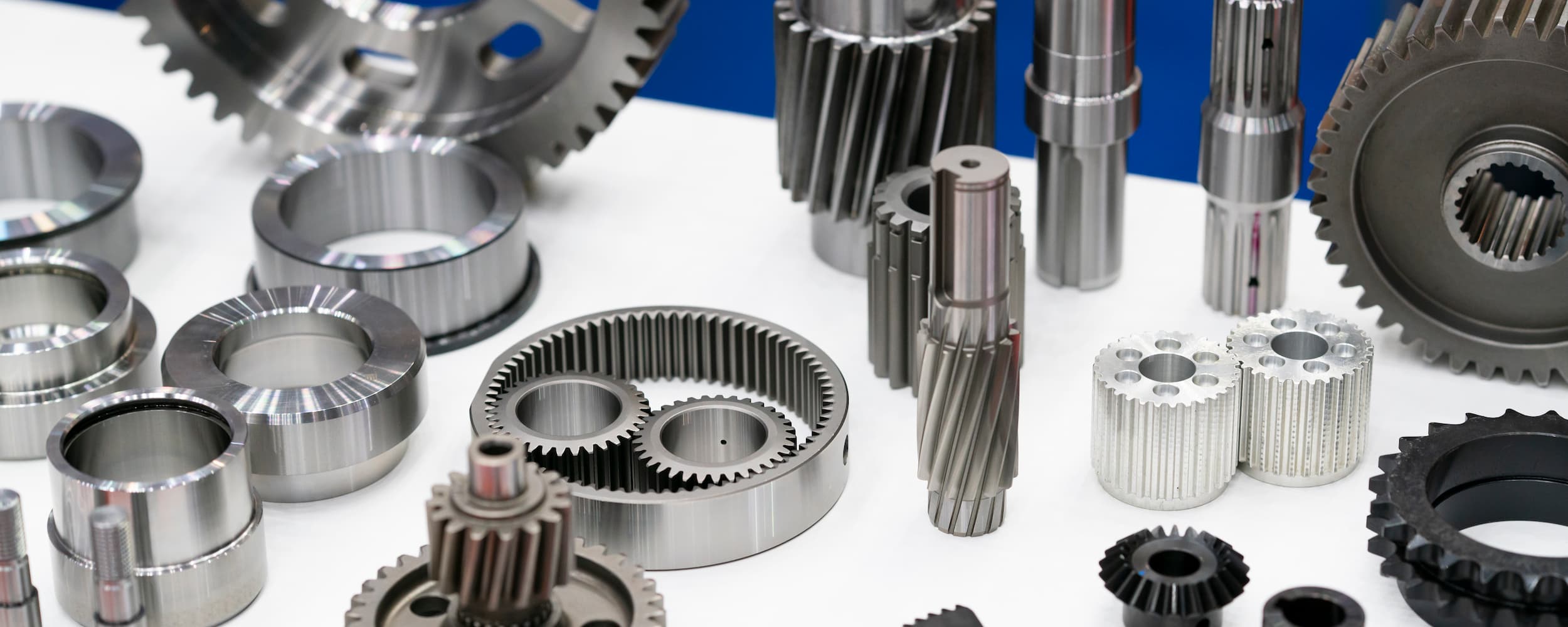 Collection of metal gears and mechanical parts on a white surface with a blue background