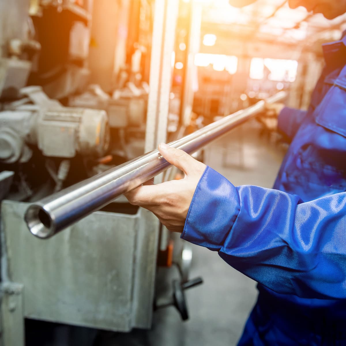 Person in blue jacket holding a metal pipe in an industrial setting