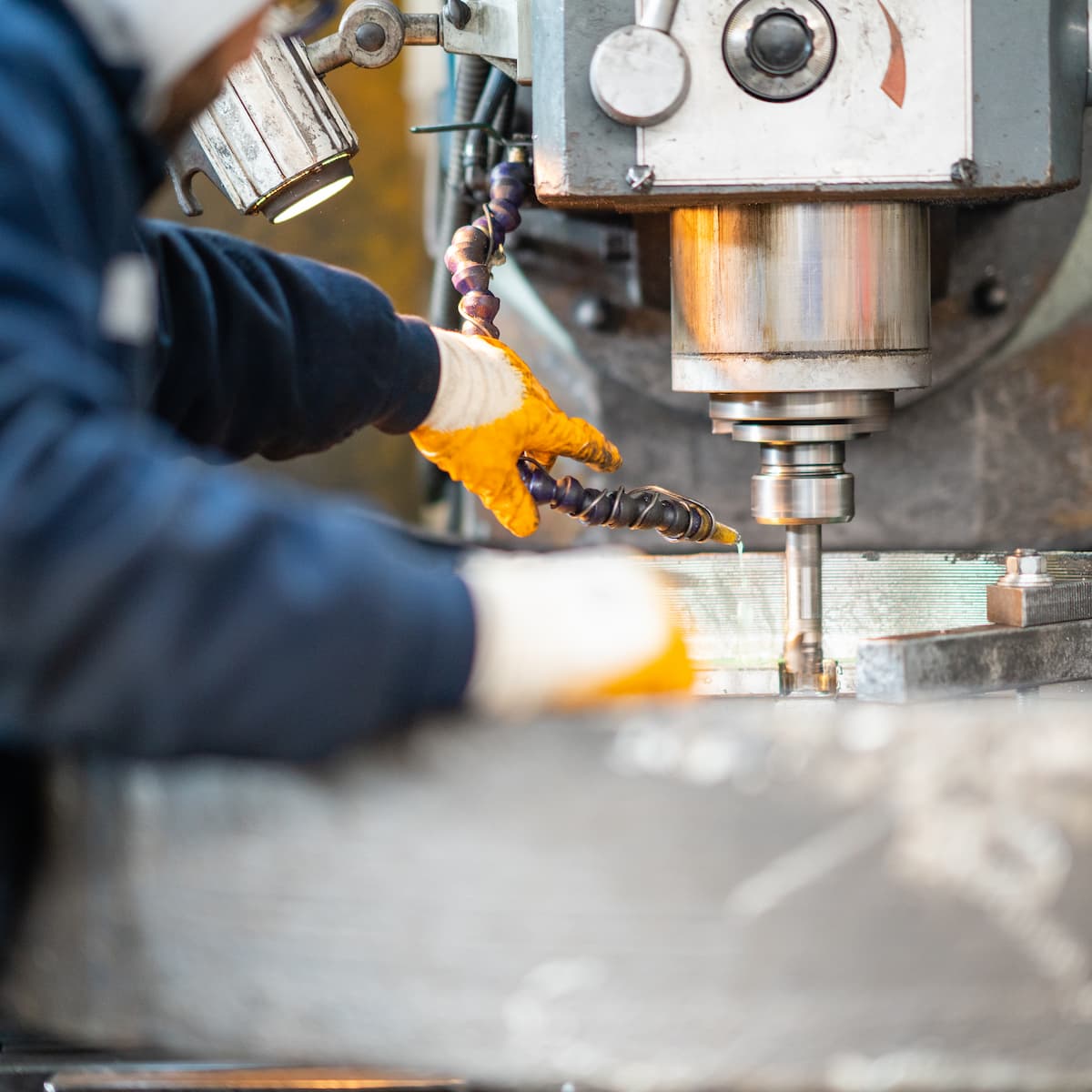 Person operating a drill press in a workshop setting