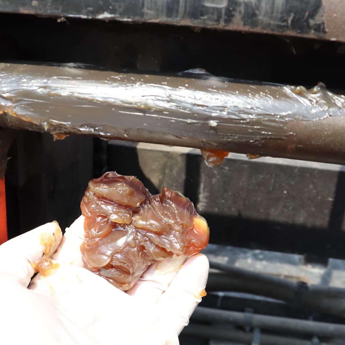Thick grease held in hand next to a machine
