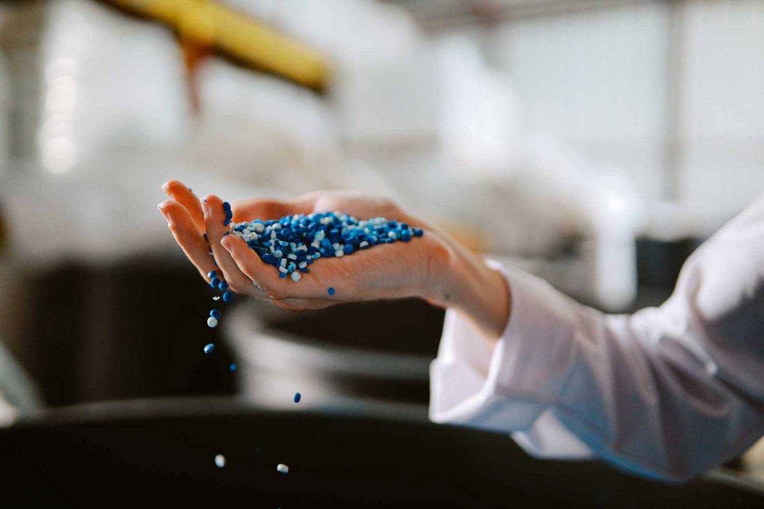 Hand holding blue plastic pellets with a blurred background