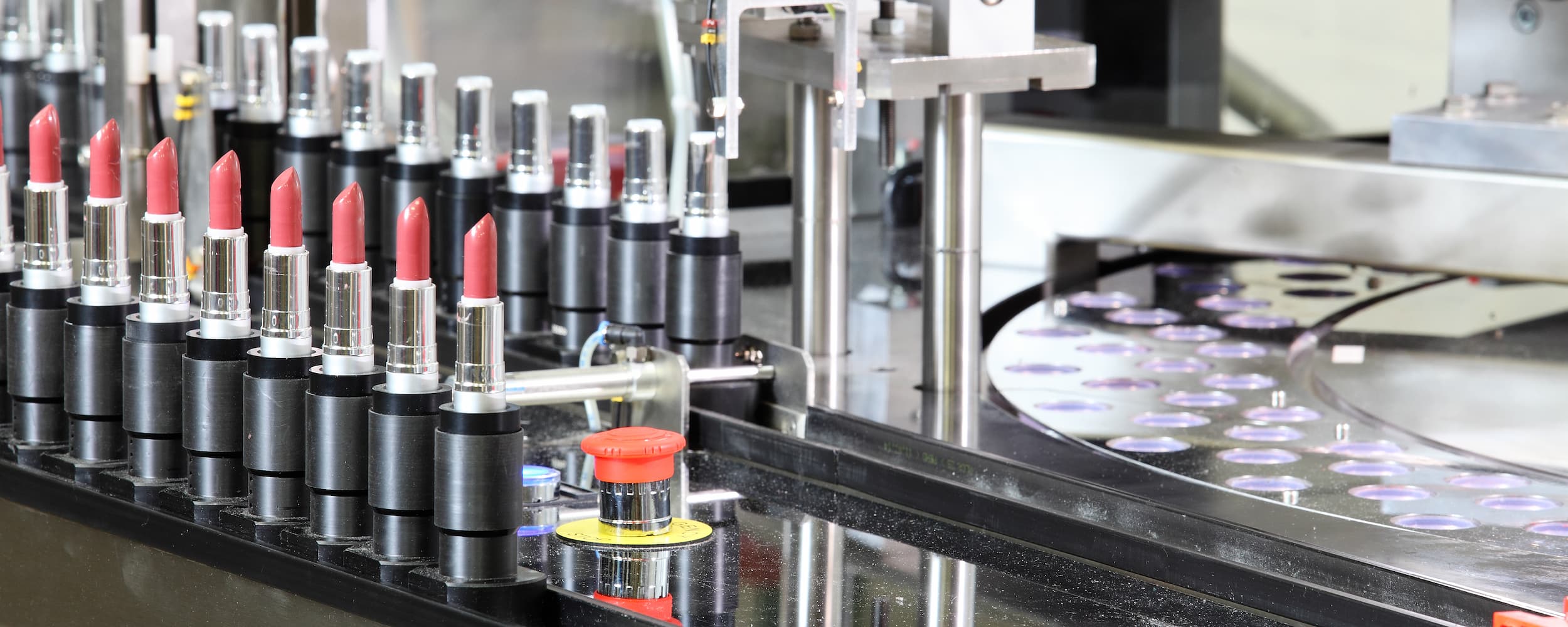 Row of lipsticks on an assembly line with a focus on manufacturing.