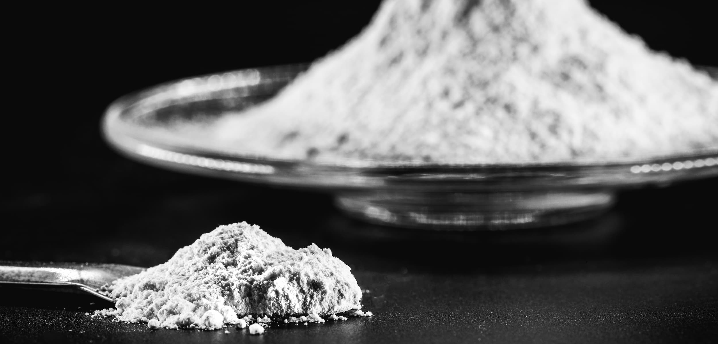 Powder on a spoon and in a dish against a black background