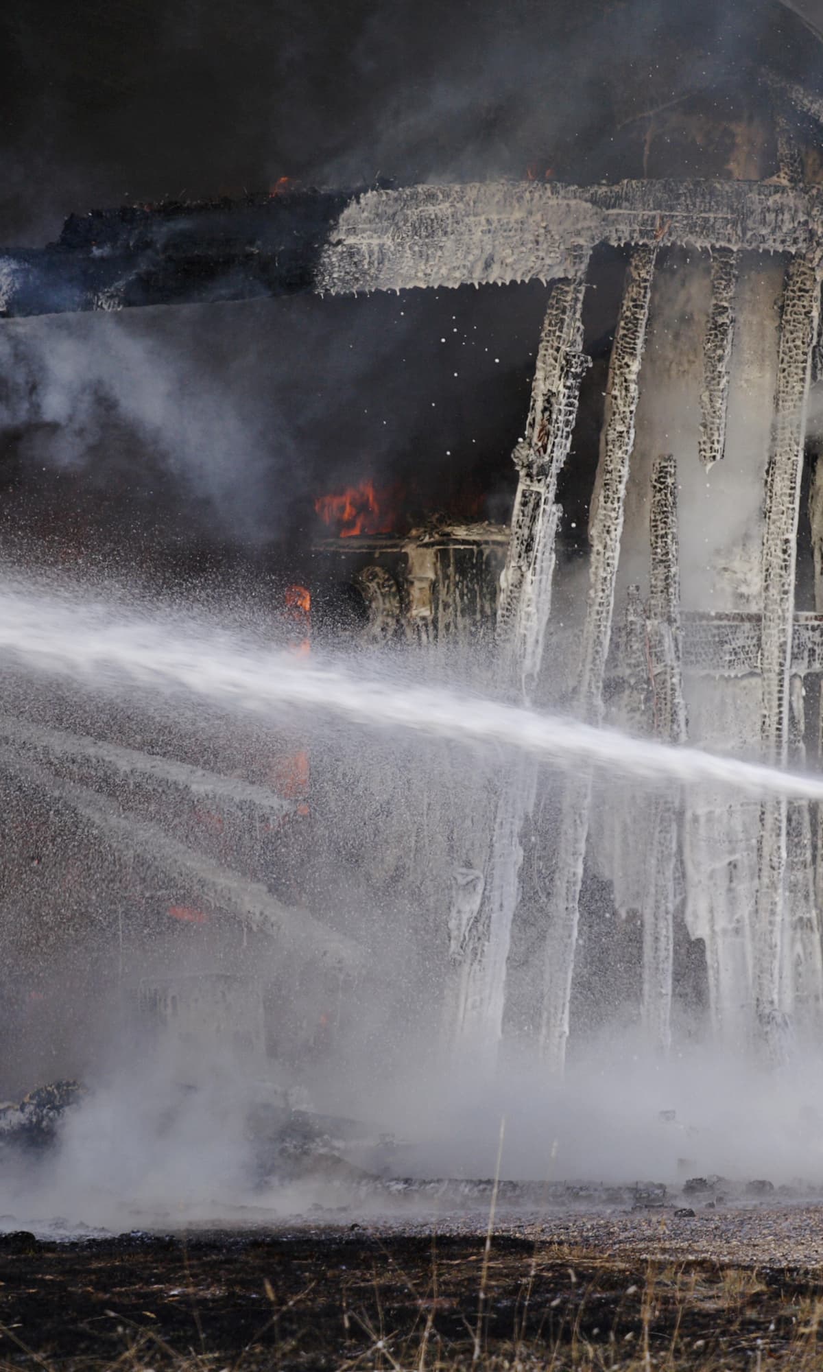 Firefighters extinguishing a fire with water streams in a dark setting