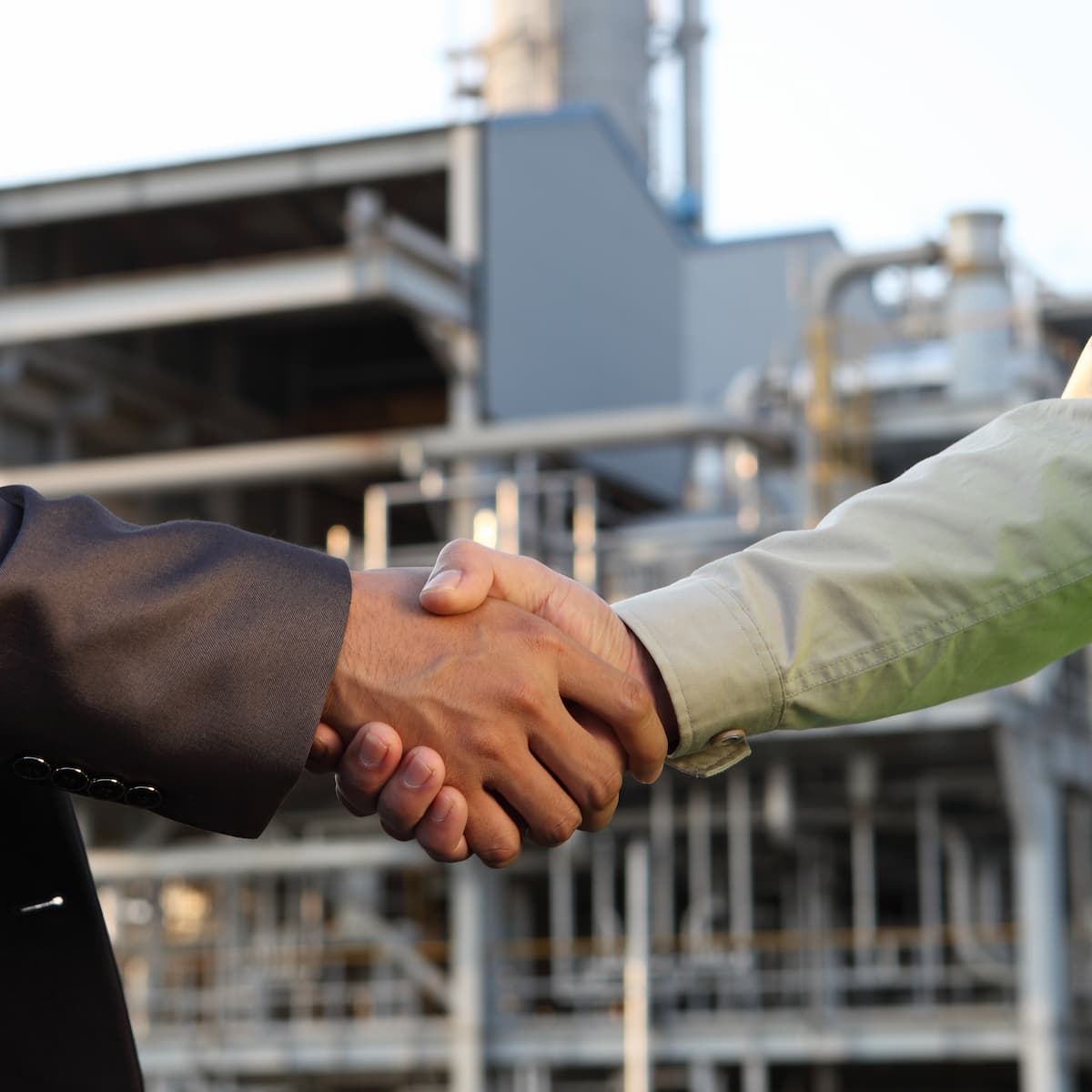 Two people shaking hands with an industrial background