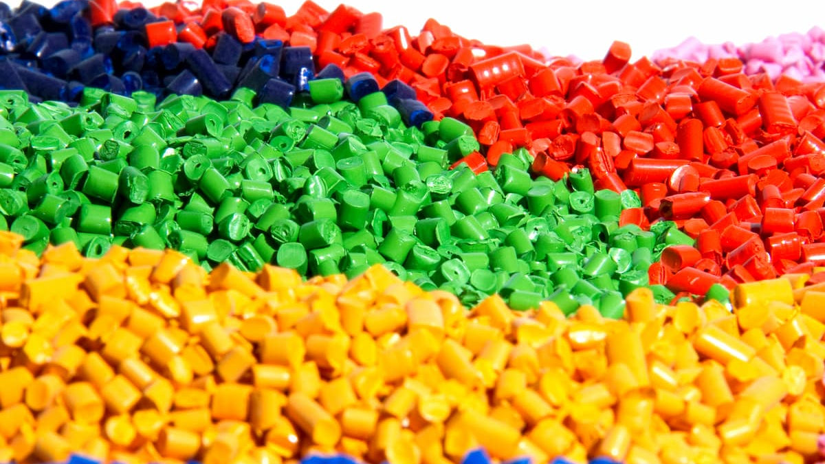 Colorful plastic pellets in red, green, orange, and blue on a white background