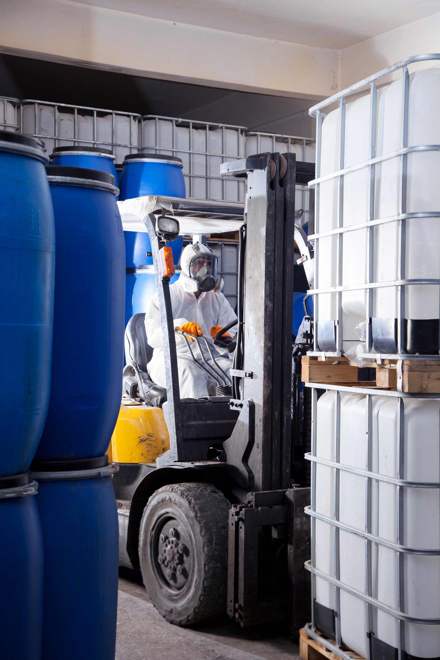 Person using a forklift to handle large industrial containers in a warehouse setting