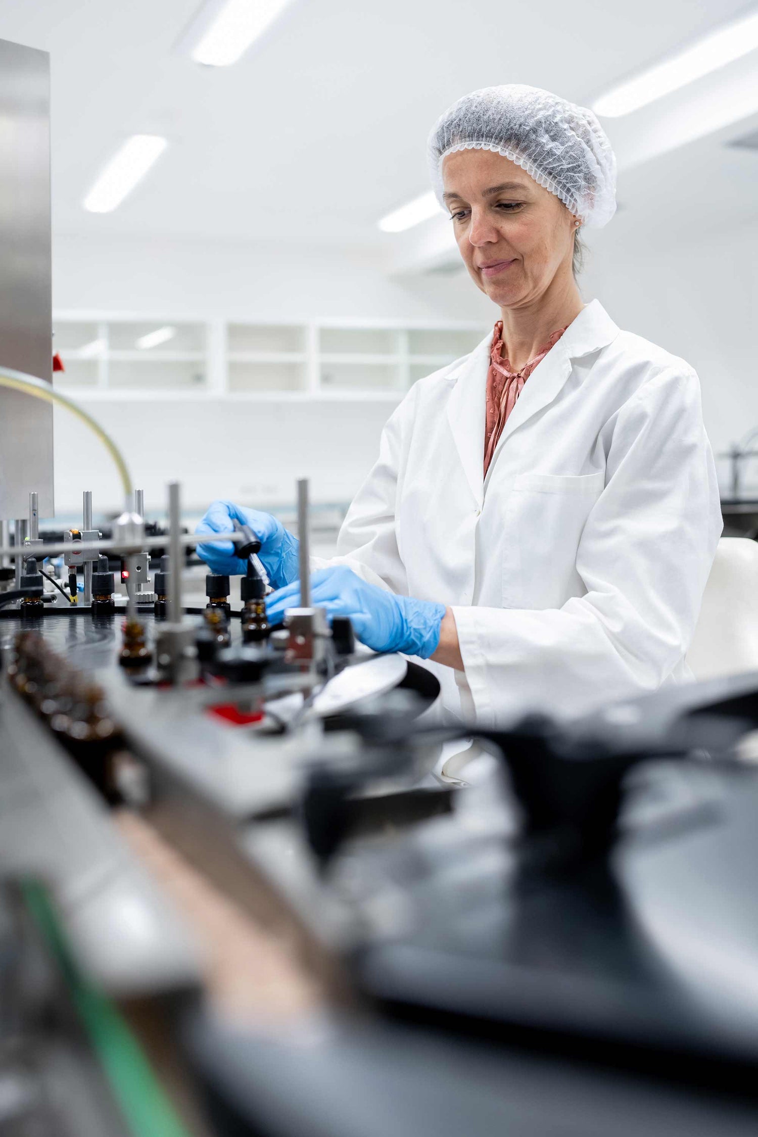 Person in a lab coat and hairnet working in a laboratory setting.