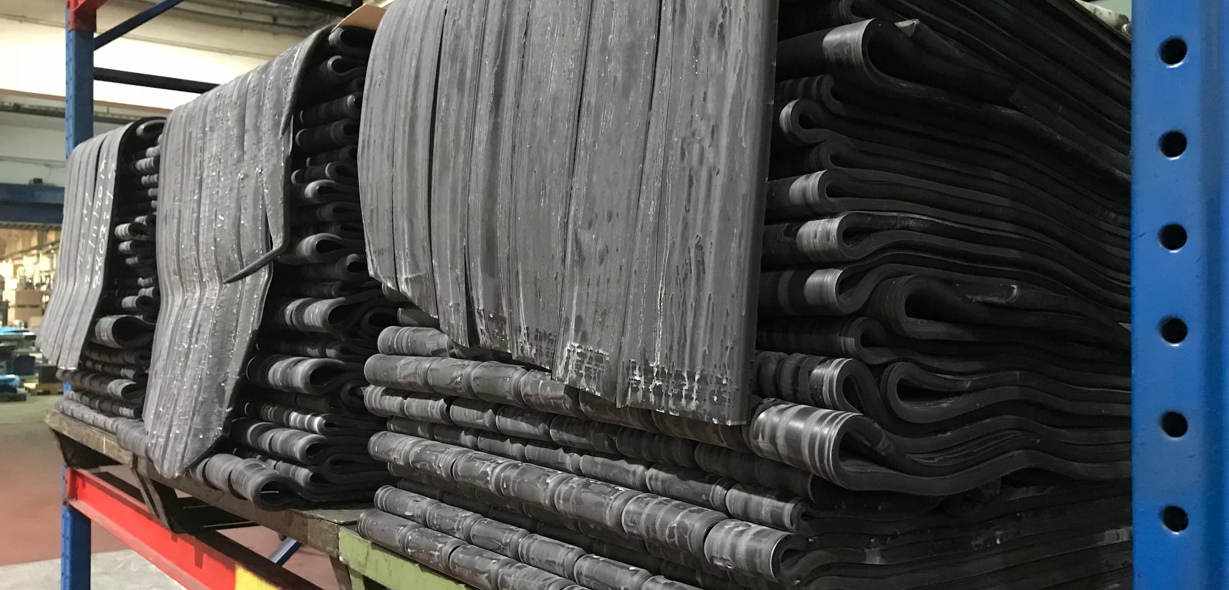 Stacks of rubber mats on a rack in an industrial setting